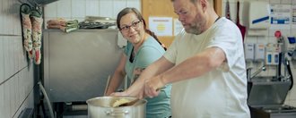 Haus am See Zwei Personen die in der Küche kochen.