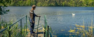 Haus am See Eine Person die vor einem See steht.