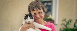 Haus am See Eine Person die eine Katze im Arm hält.